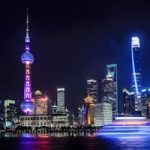 Stunning night view of Shanghai skyline with illuminated skyscrapers and the Oriental Pearl Tower reflecting in the water.